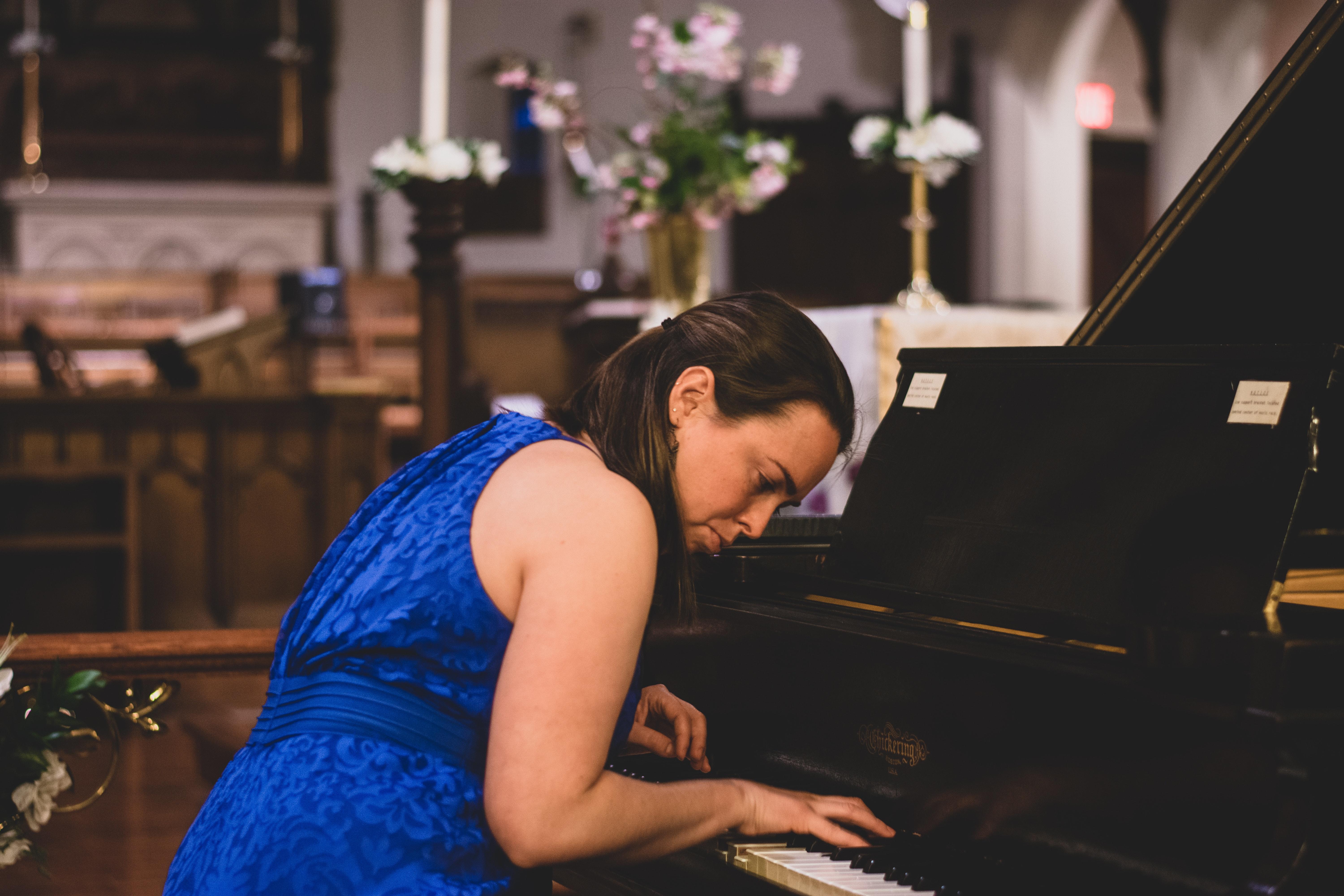 Mujer ciega en vestido azul tocando el piano en una iglesia.