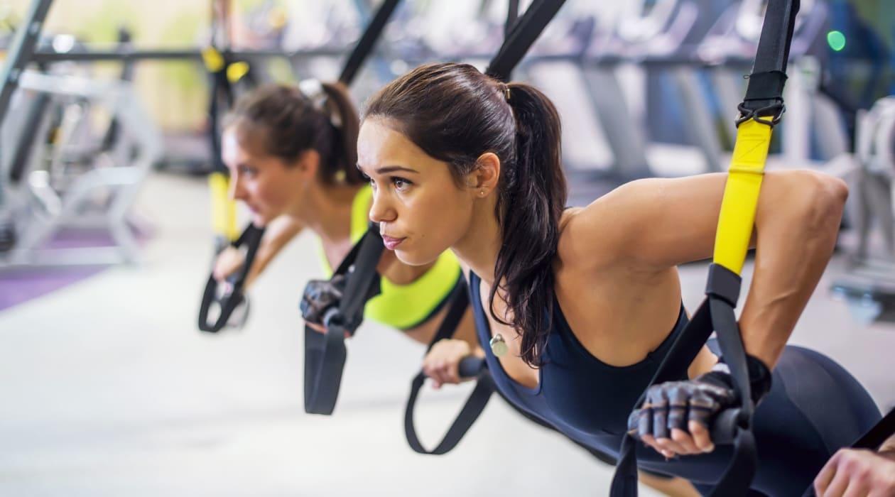 Chica realizando TRX junto a una compañera