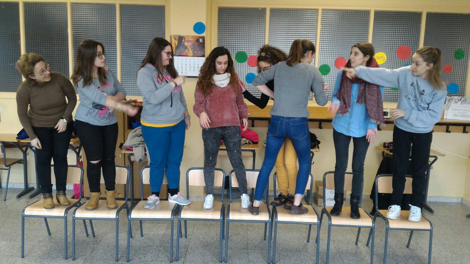 8 chicas sobre 8 sillas en un aula de clase durante una actividad lúdico pedagógica.