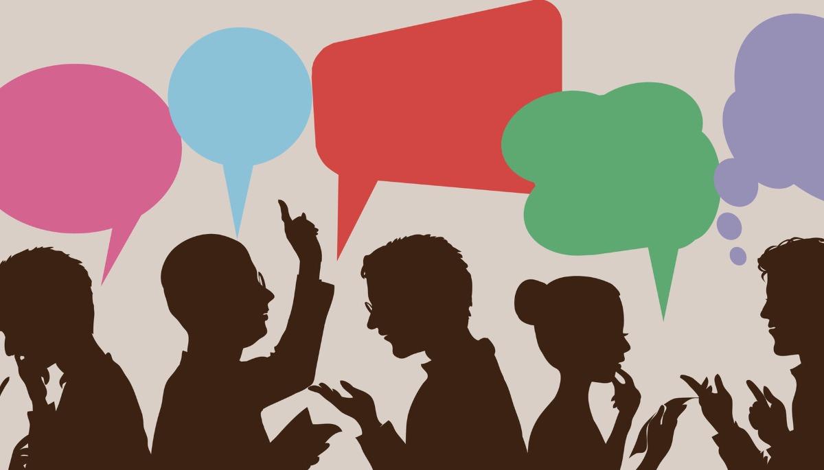 Siluetas de personas que entablan una conversación figurativa con globos comunicativos de colores.