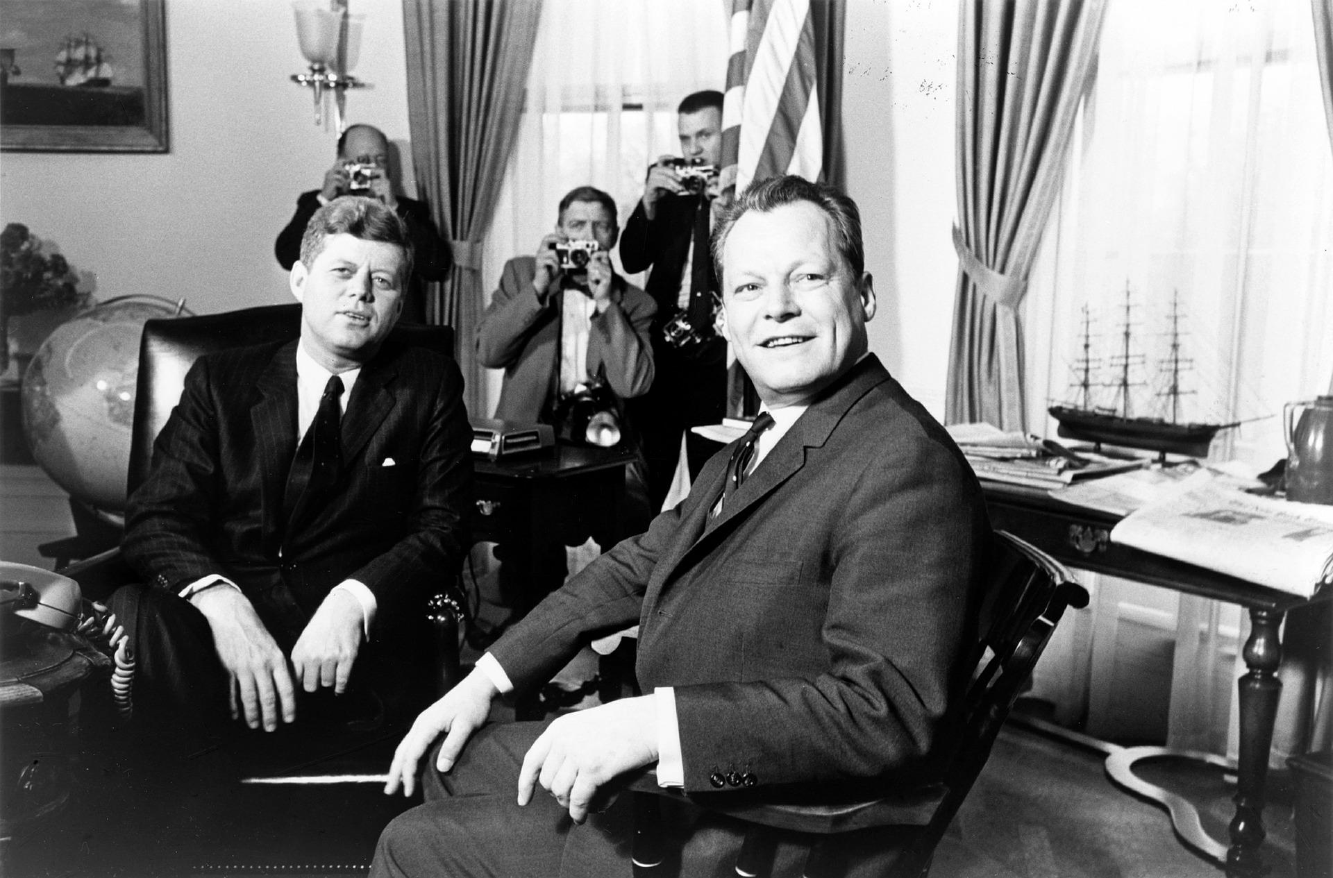 Foto a Blanco y negro de John F. Kennedy y Willy Brandt, viendo con una sonrisa a la cámara.