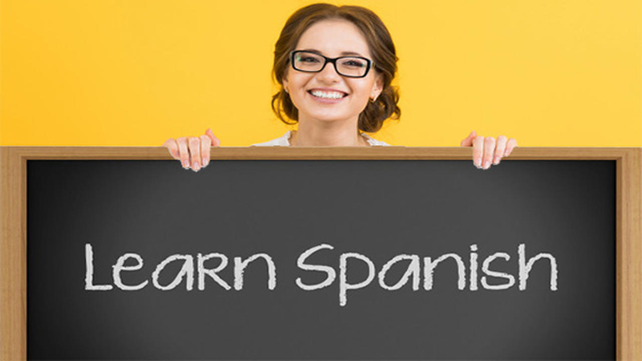 Profesora de español con una pizarra en al que dice "learn Spanish".