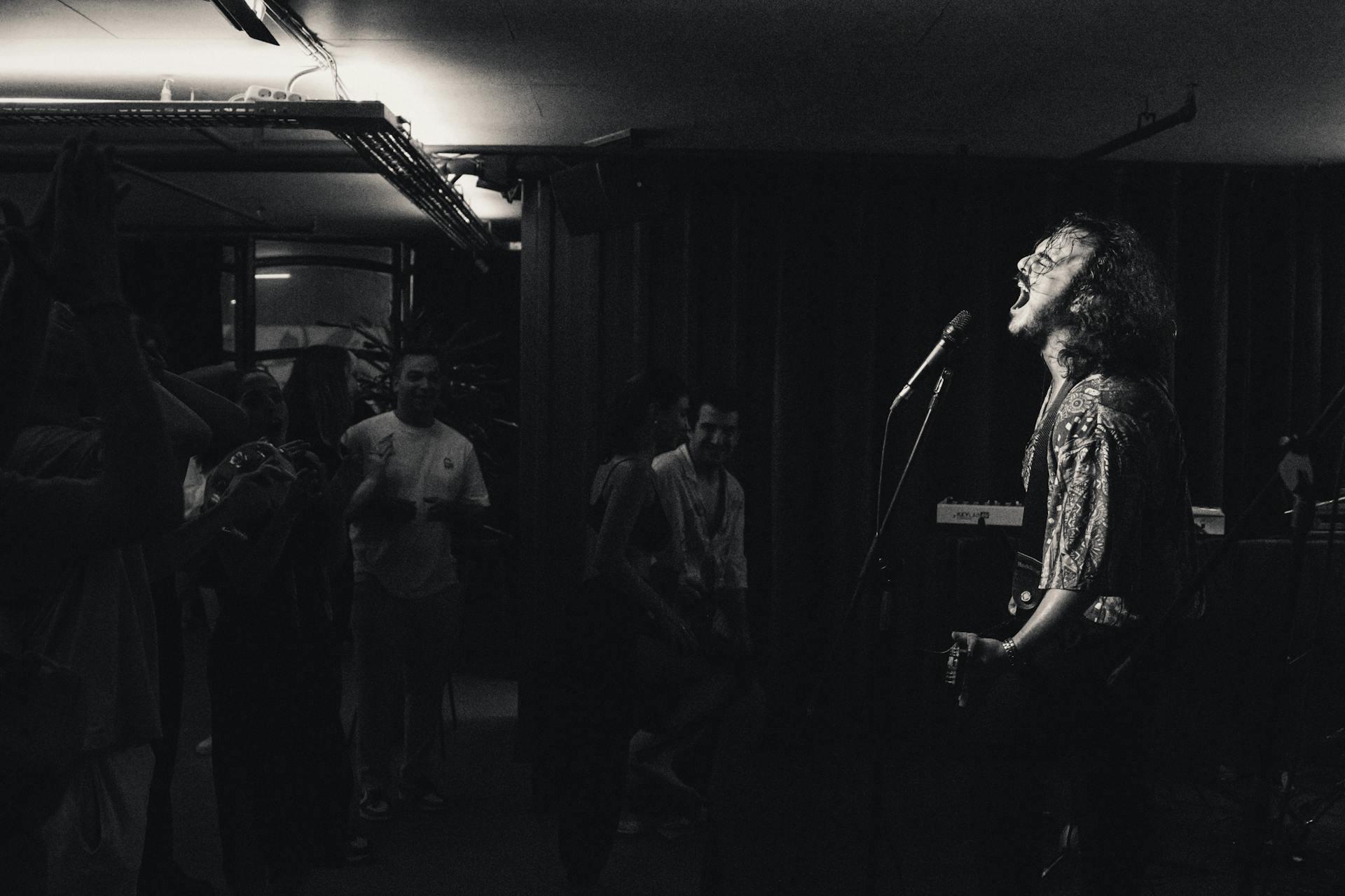 Hombre cantando en un concierto con una guitarra. Imagen a blanco y negro