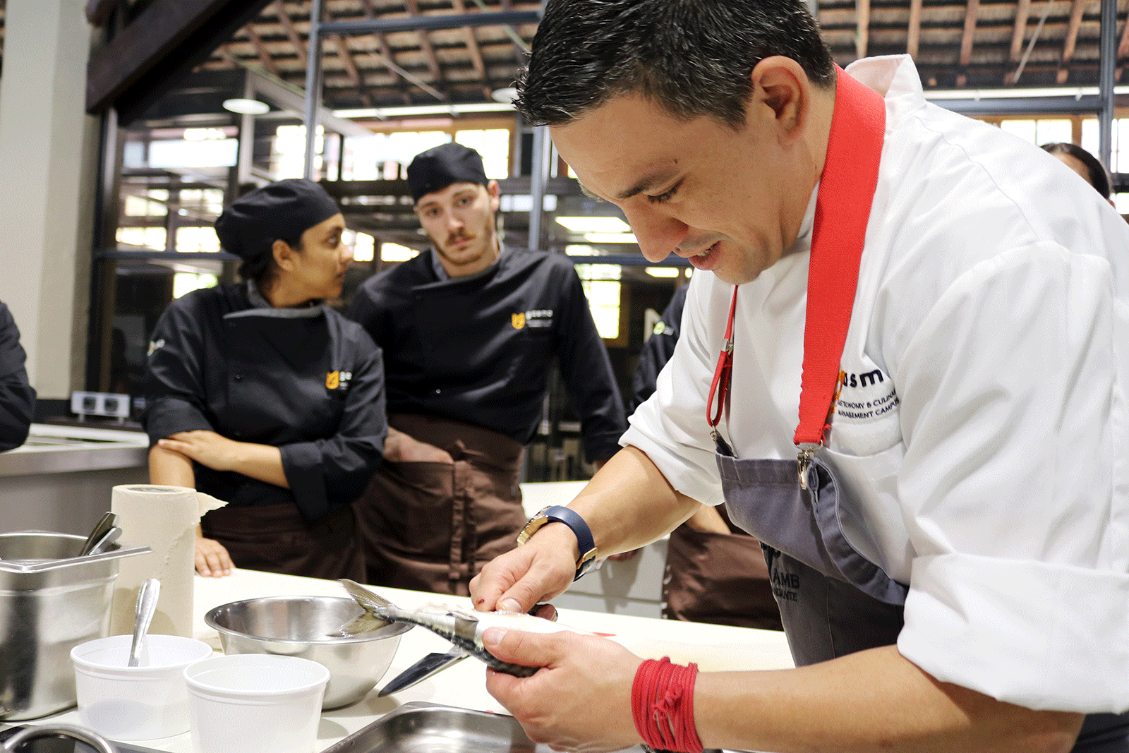 Chef dando una demostración de cómo se descama el pescado.