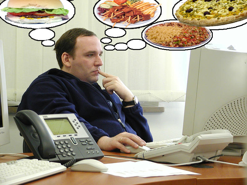 Hombre trabajando mientras piensa en la hora de salir y qué almorzar.