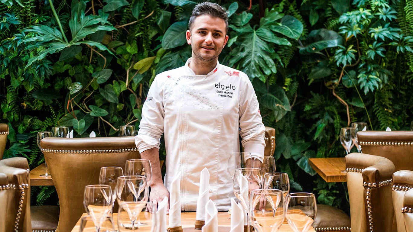 Cocinero listo detrás de una mesa llena de copas