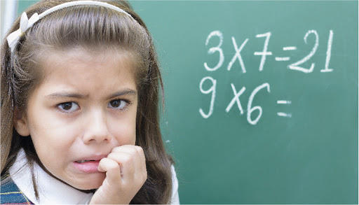 chica aterrada con multiplicaciones escritas en la pizarra en el fondo