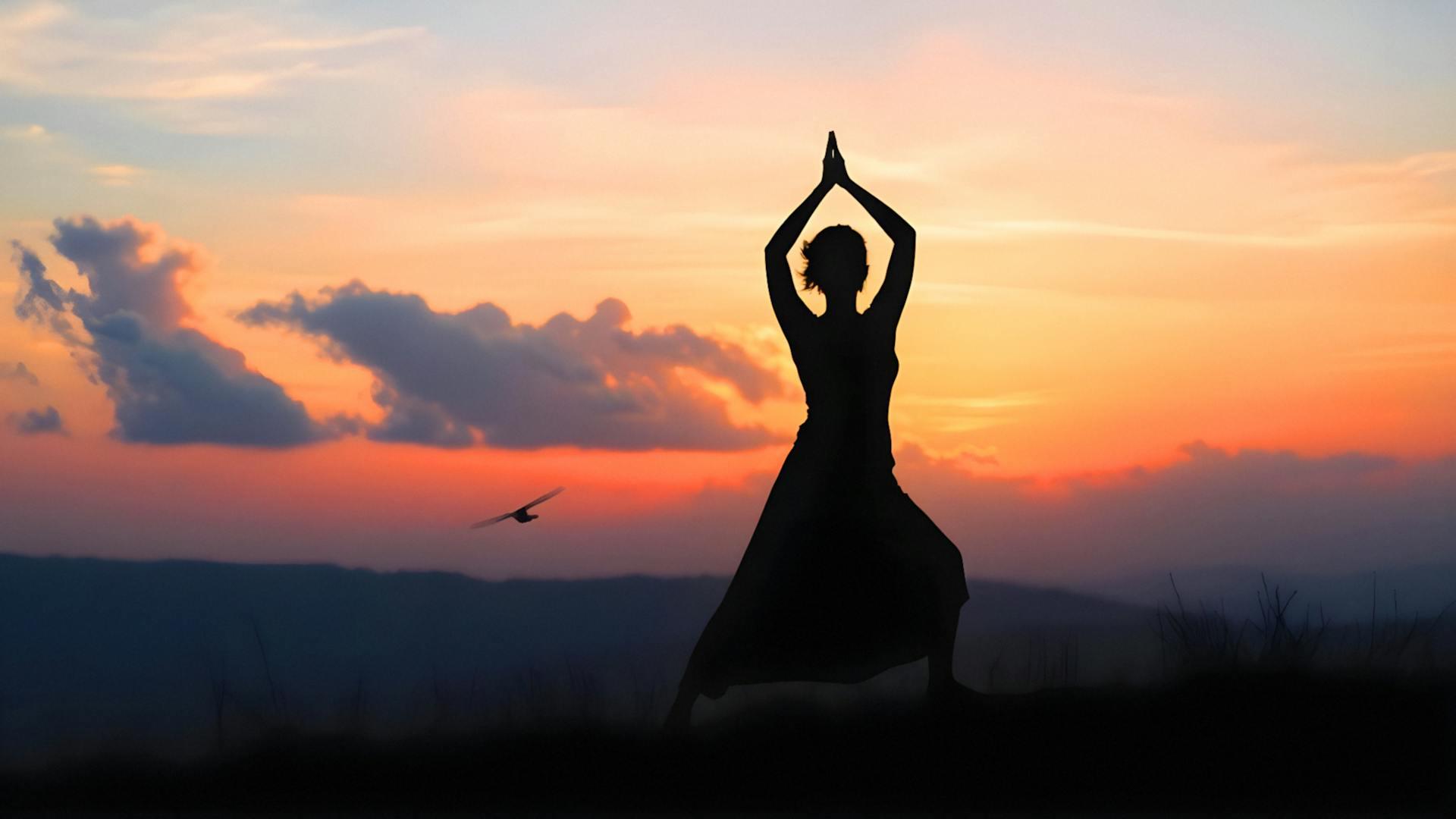Imagen de un atardecer con una sombra de una mujer haciendo hatha yoga