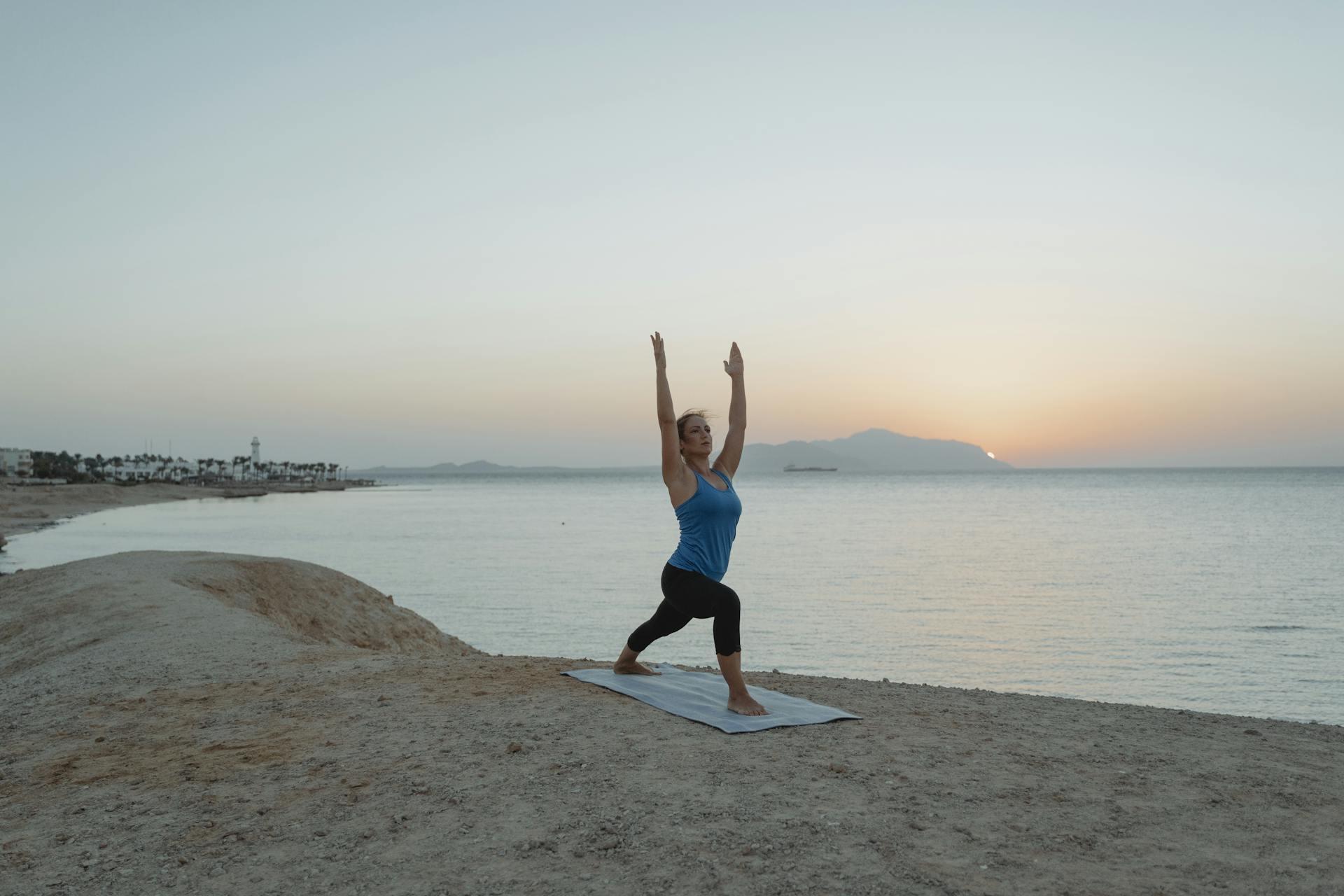 Mujer en el mar haciendo yoga Postura del Guerrero (Virabhadrasana)