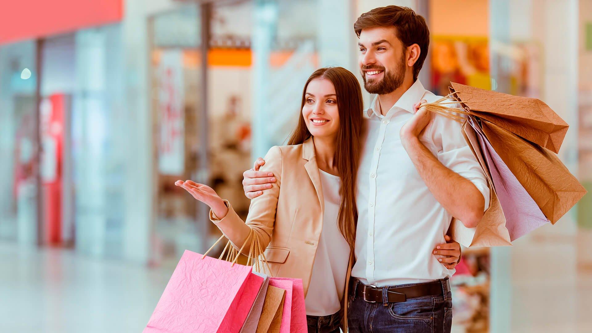 Pareja sonriendo, con bolsas de compras en sus manos.