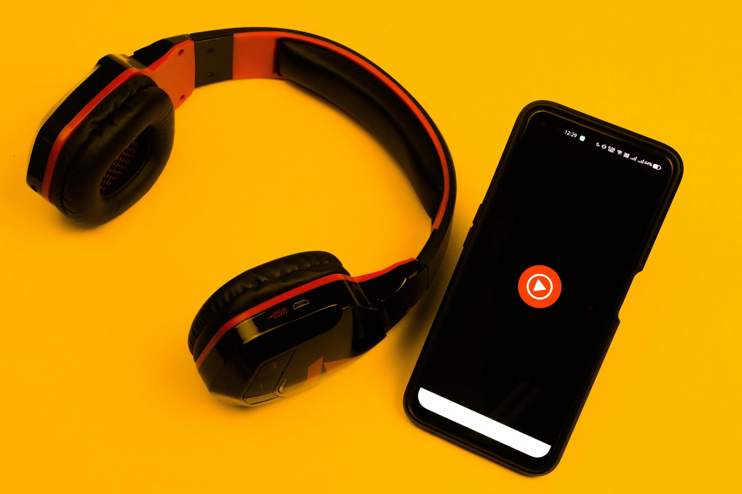 celular con un audífonos en una mesa amarilla