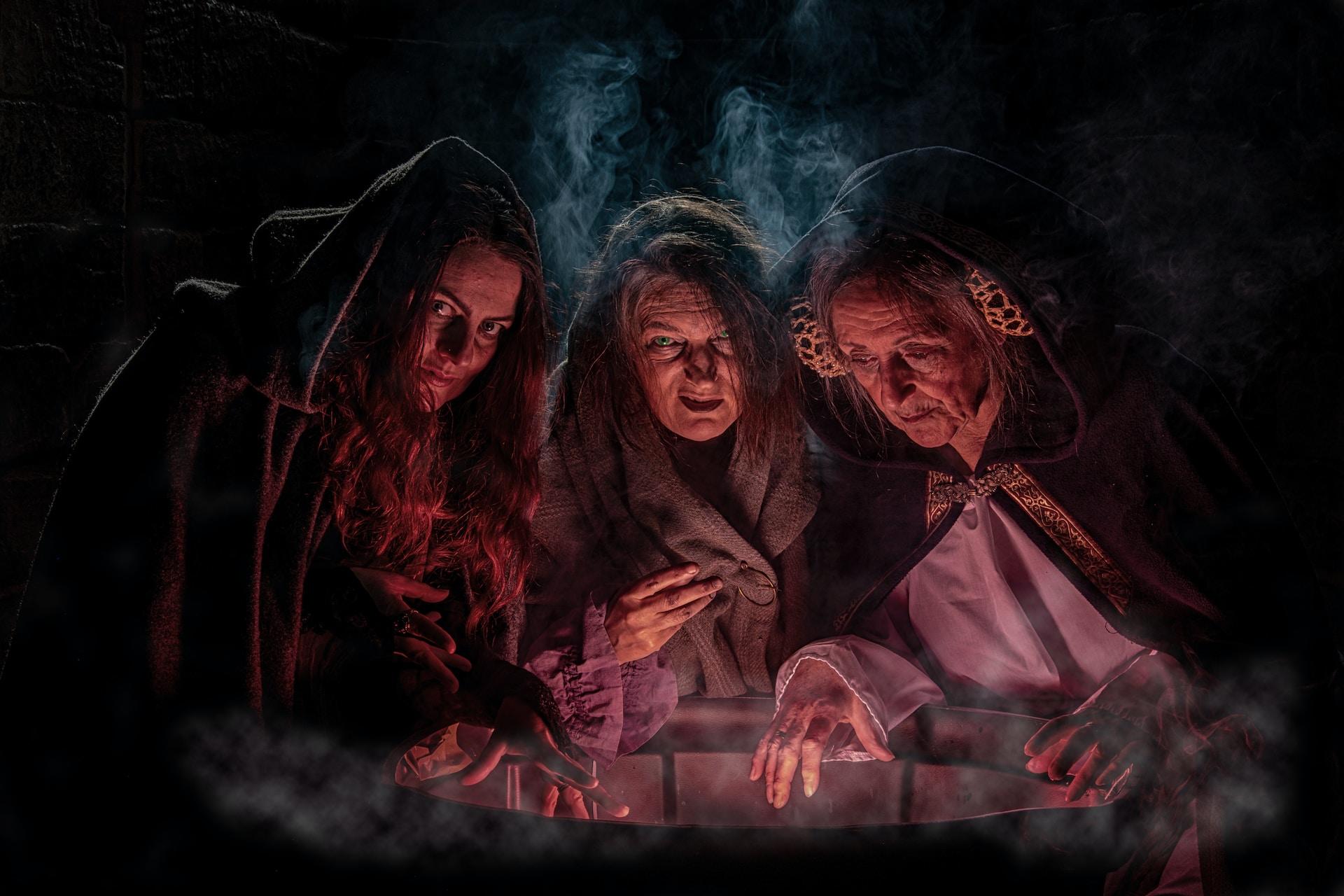Chicas con aspecto de brujas reunidas alrededor de fuego