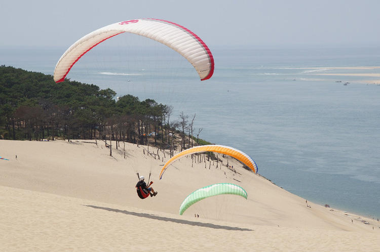 Turista, cayendo en parapente, a la duna de Pilat.