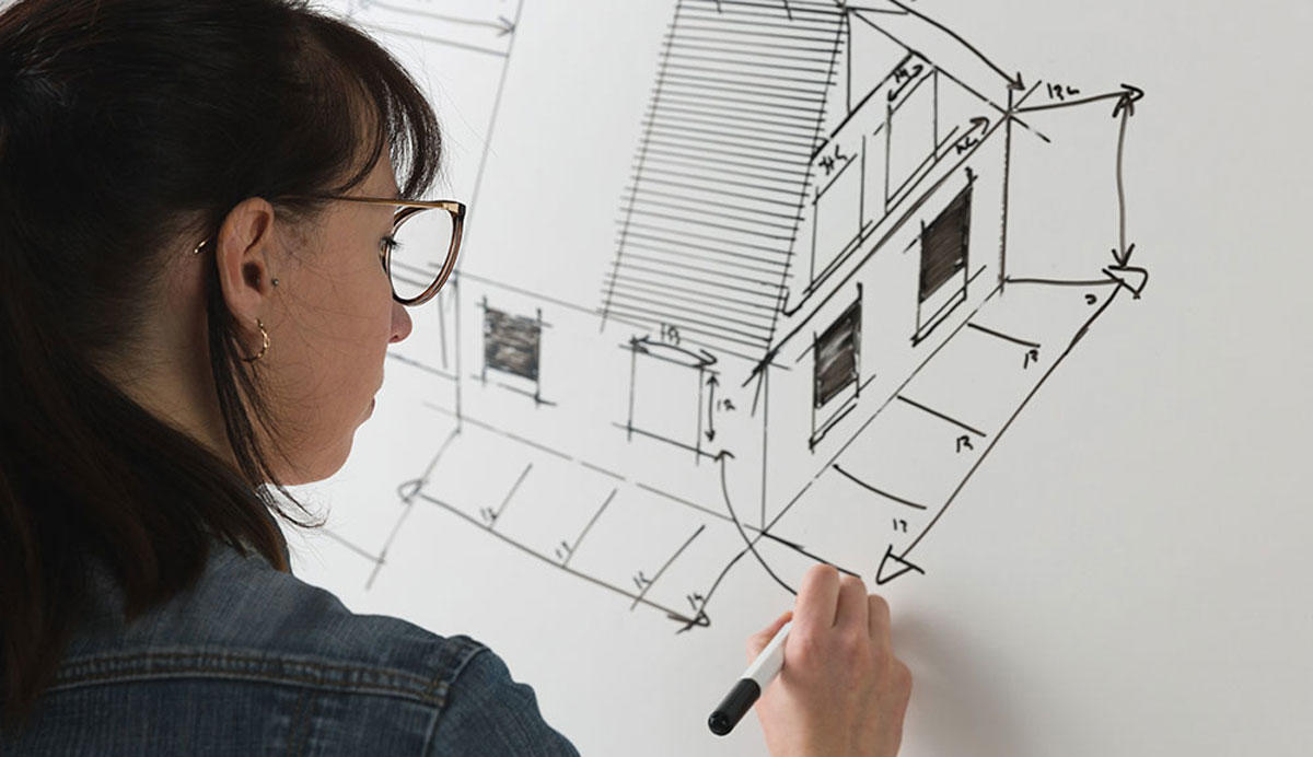 Chica terminando de dibujar el plano de una casa.