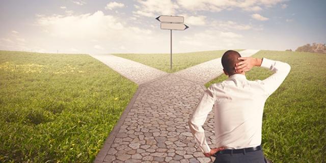 Hombre de espaldas decidiendo si tomar el camino de la izquierda o la derecha