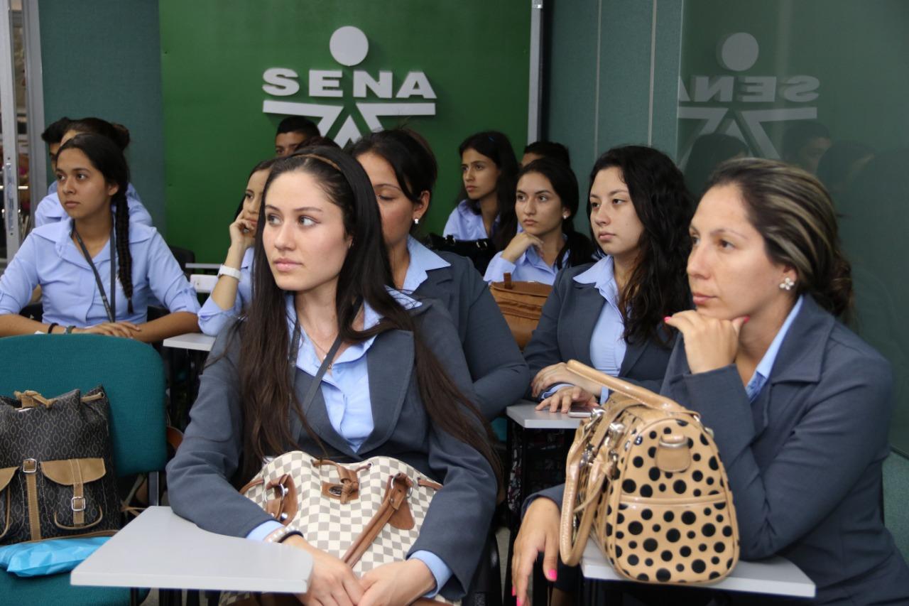Estudiantes en salon de clases, el logo del SENA al fondo