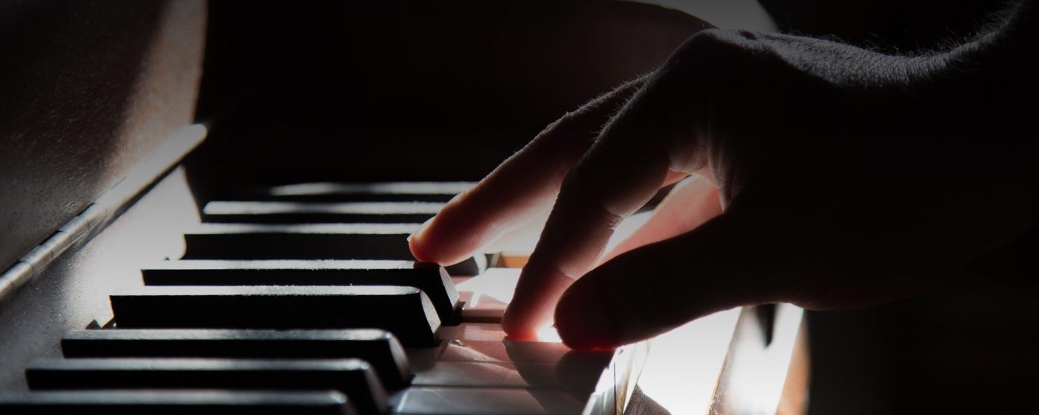 Mano derecha sobre piano con fondo negro