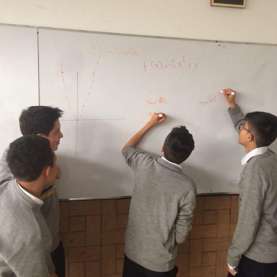 Jóvenes frente a un tablero escribiendo expresiones matemáticas.