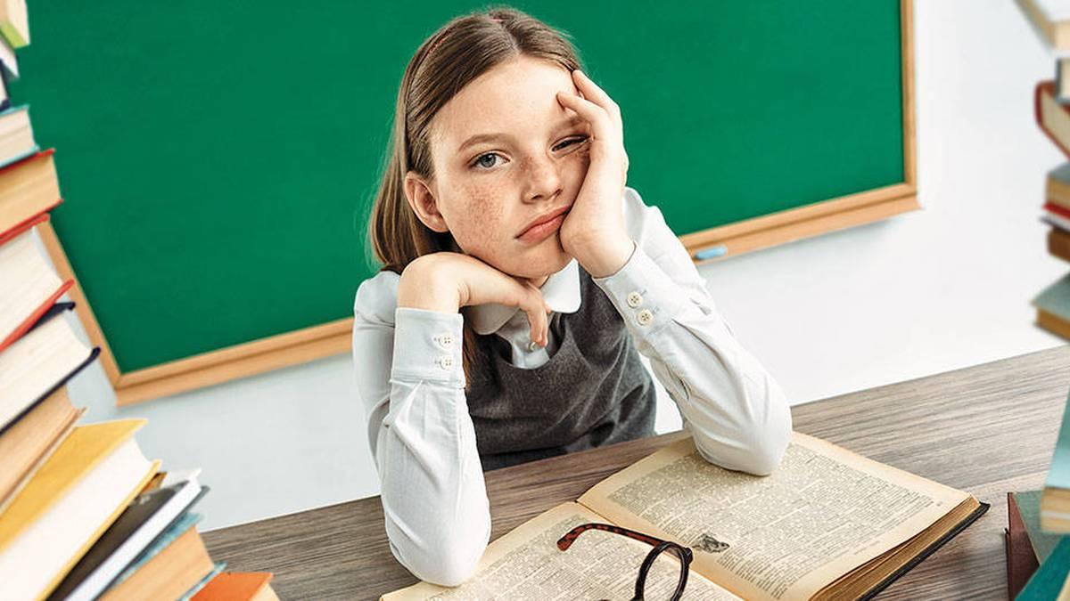Niña con una mano en la cara y una expresión aburrida.