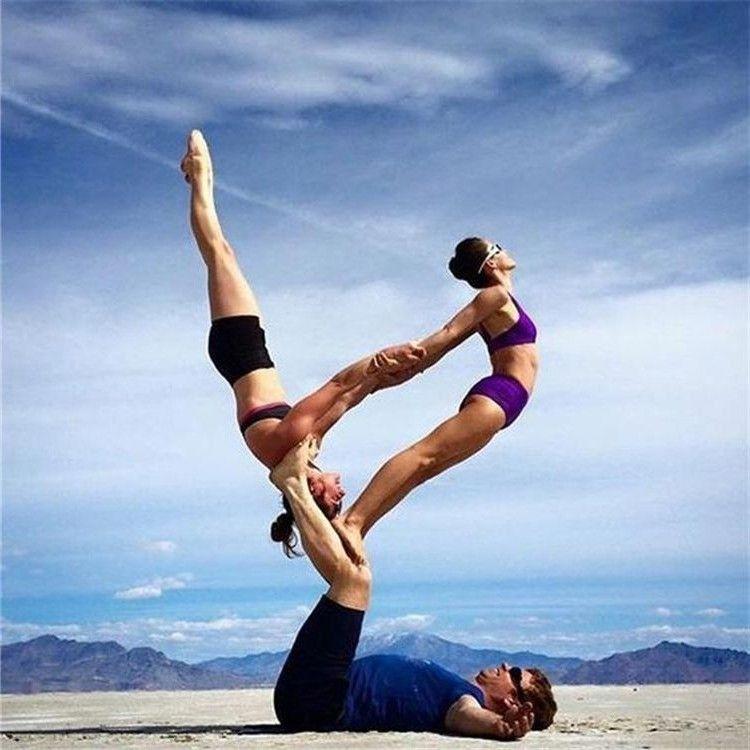 Hombre sosteniendo a dos mujeres haciendo acrobacias de yoga