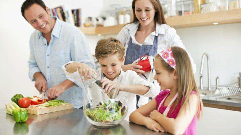 Pareja de hijos con sus padres preparando una ensalada