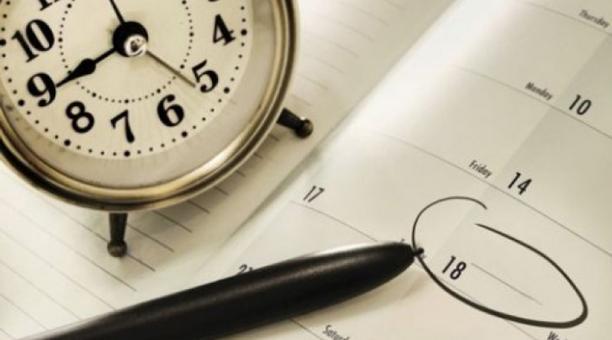 Reloj junto a un esfero y un calendario.