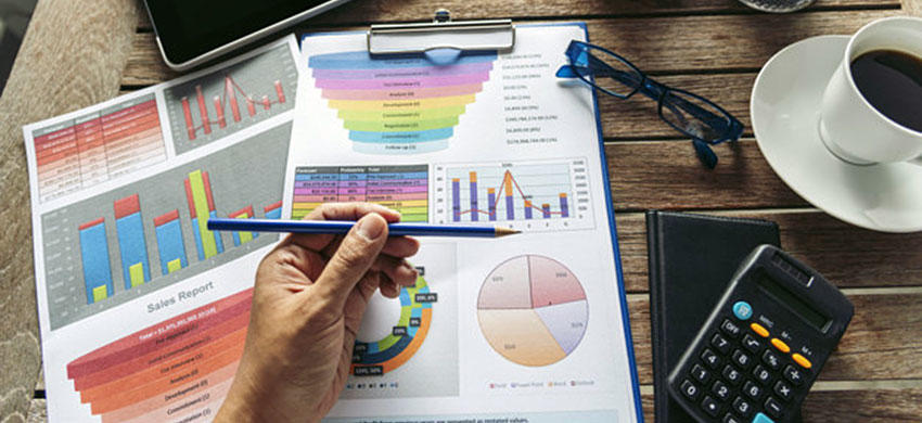 Hombre con esfero y calculadora en mano revisa cuentas que se encuentran de forma manual 