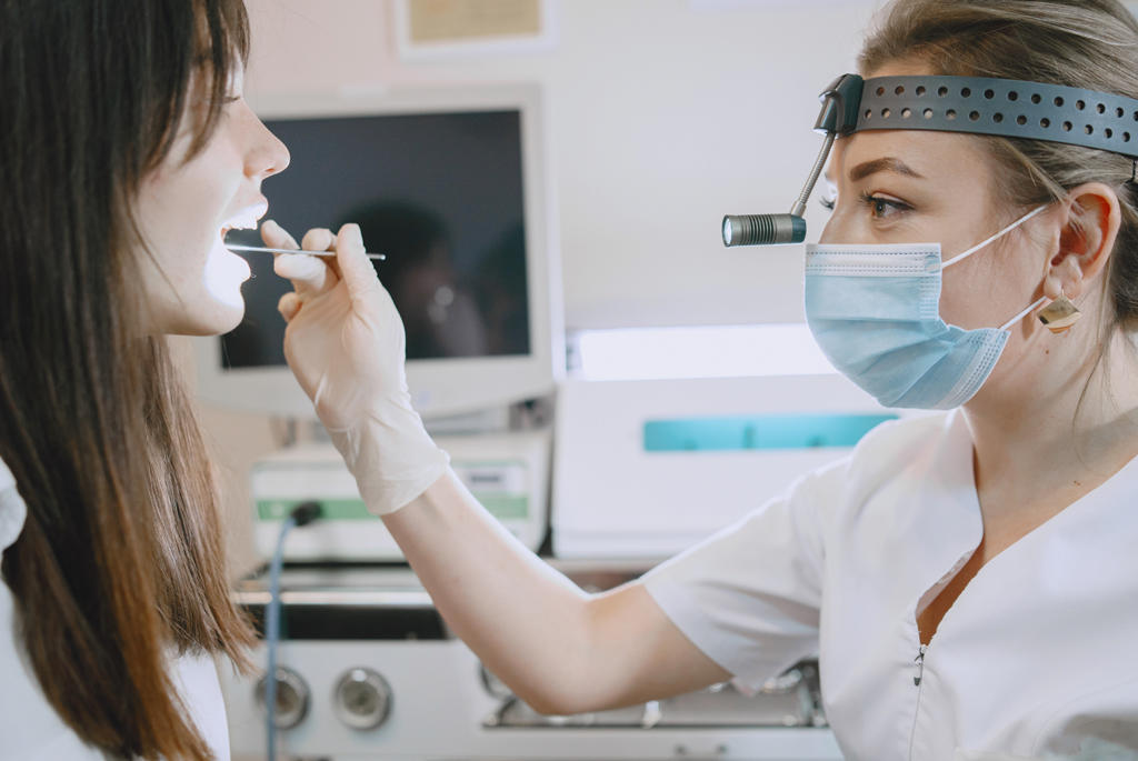 Doctora con aparatos, revisando la gargante de paciente