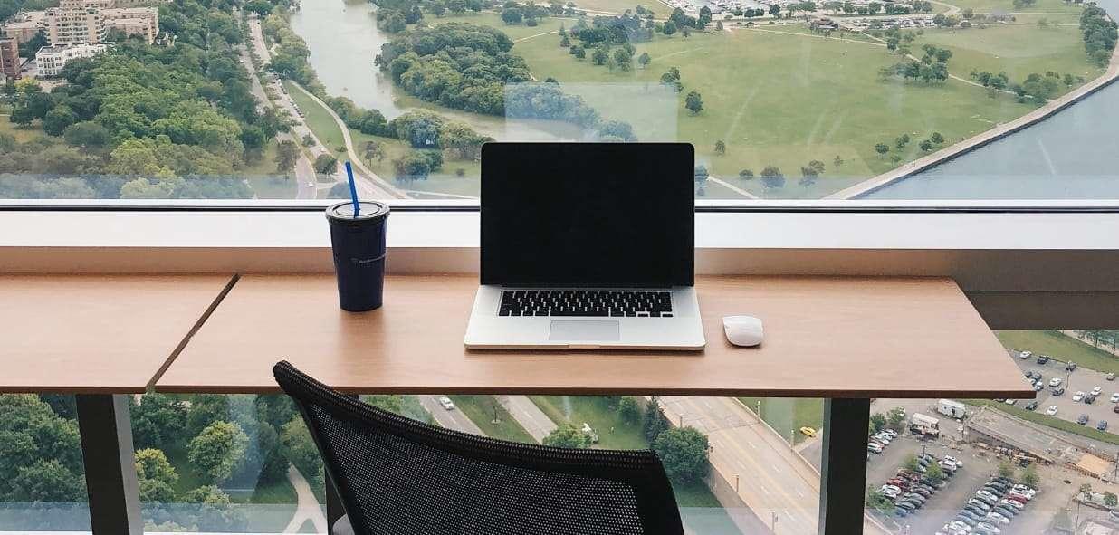 Portatil sobre un escritorio que está frente a una ventana con una buena vista de la ciudad.