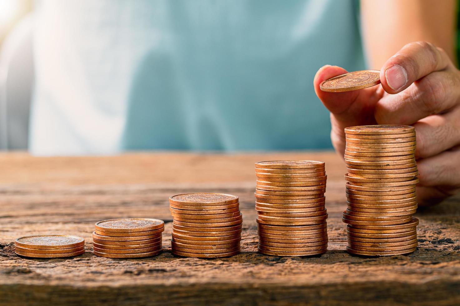 Torres de monedas con una manos colocándolas una sobre otra.