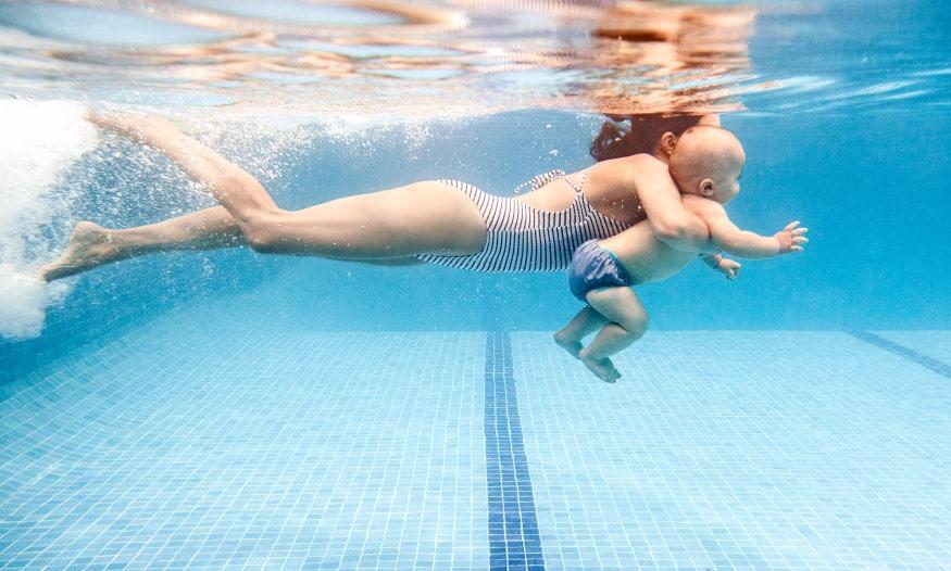 Madre flotando con su bebé en piscina