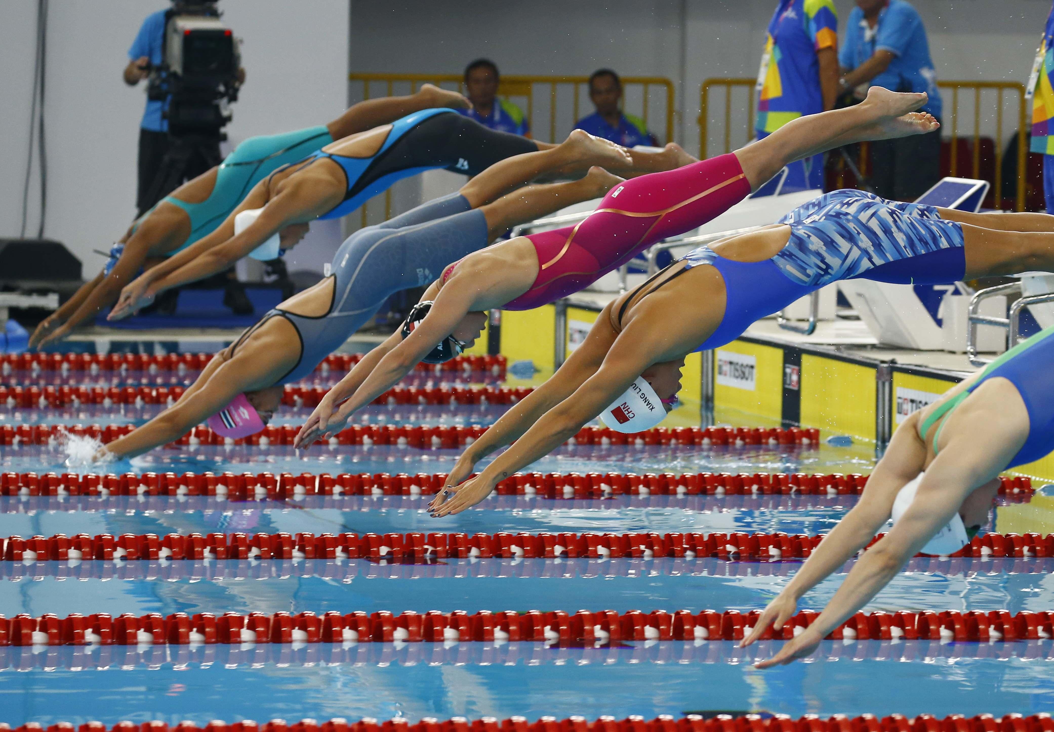 Atletas de diferentes delegaciones lanzándose al agua al inicio de una competencia de nado