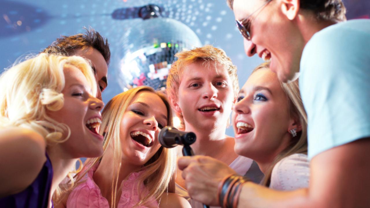 Grupo de amigos felices cantando karaoke.