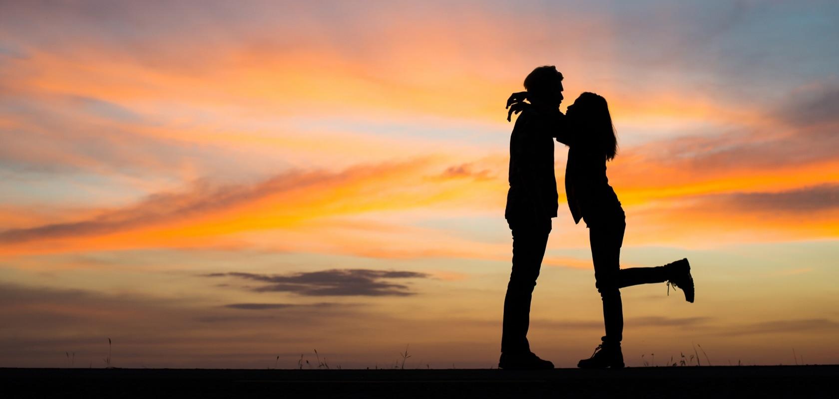 Silueta de una pareja abrazándose a contraluz de un atardecer