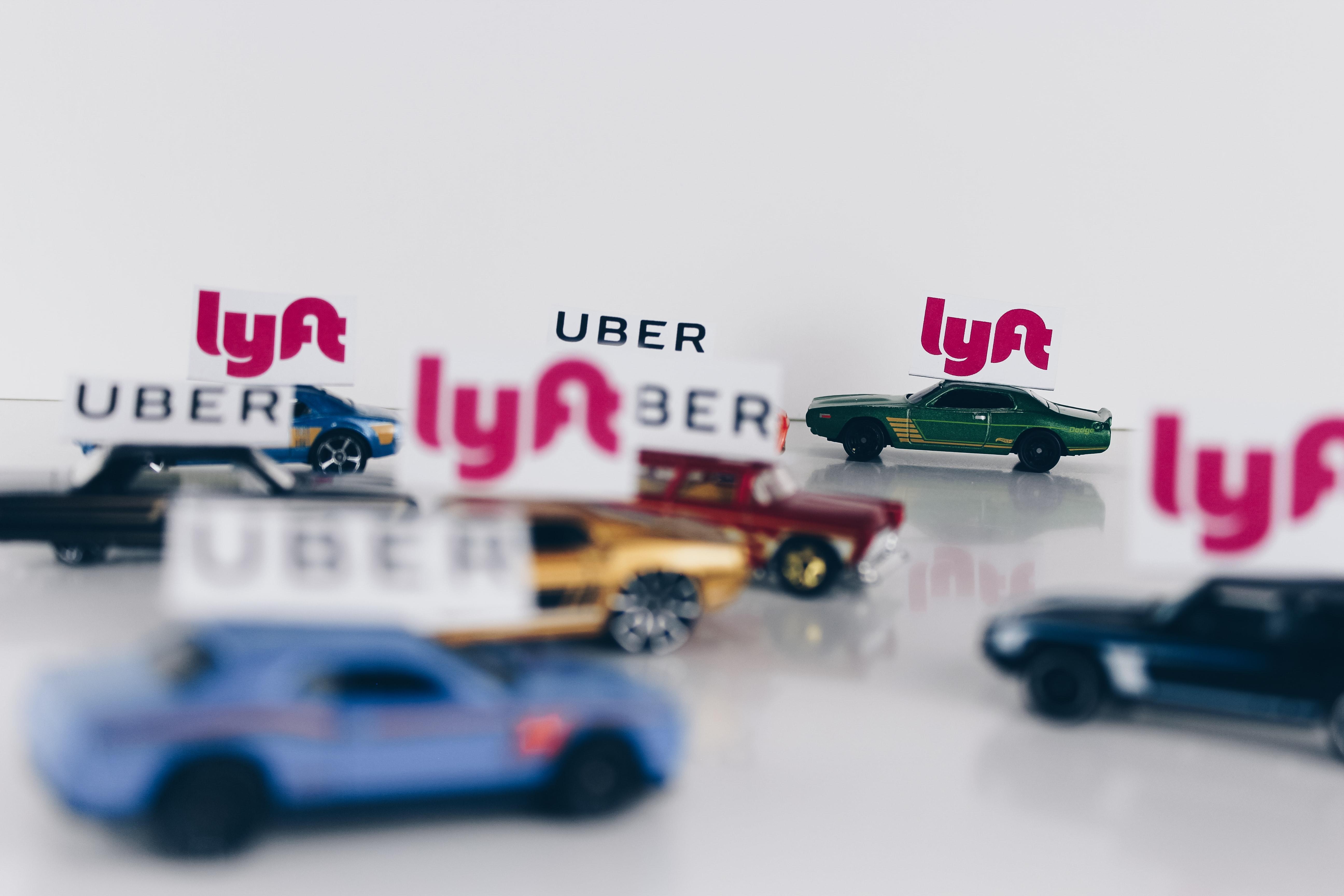Carritos de juguete en fondo blanco, con los logos de uber y Lift