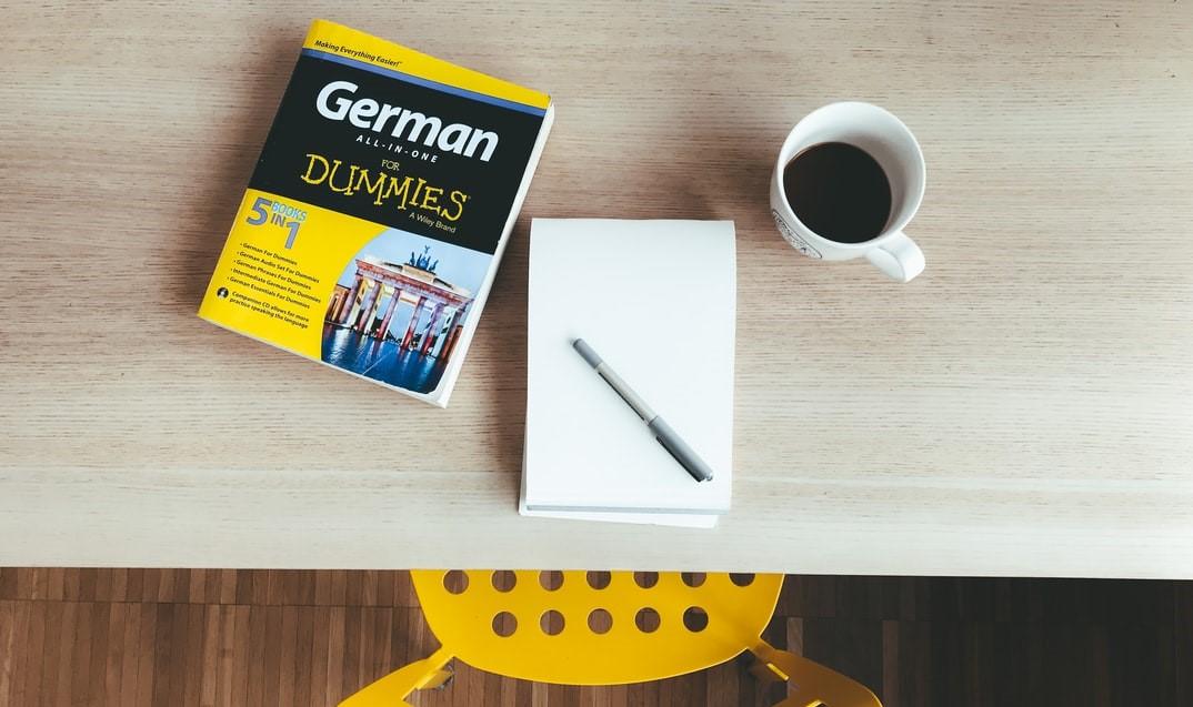 Libro de German para Dummies sobre una mesa, con libreta de notas, boligrafo y café