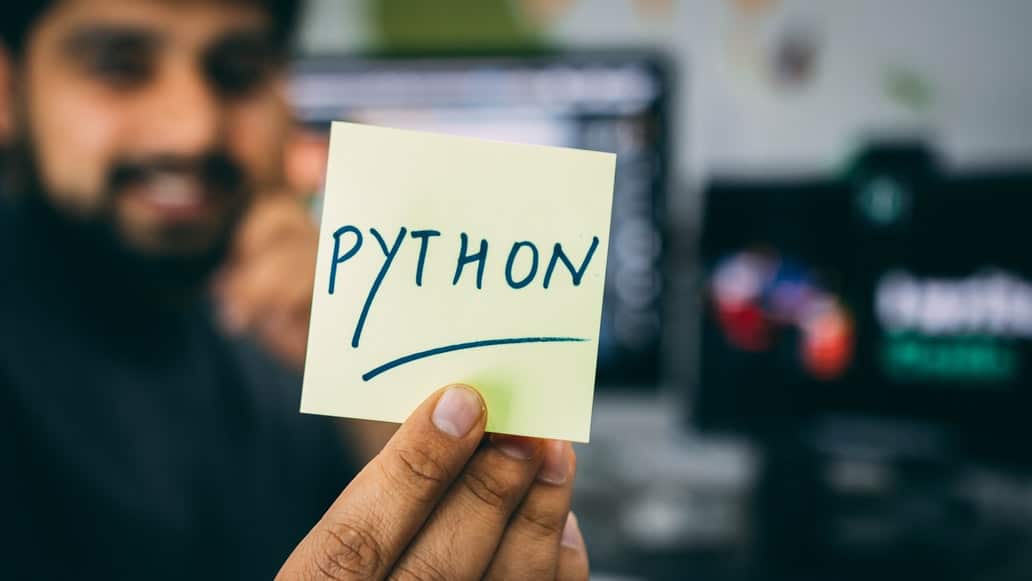 Hombre mostrando una memoficha con Python escrito en ella