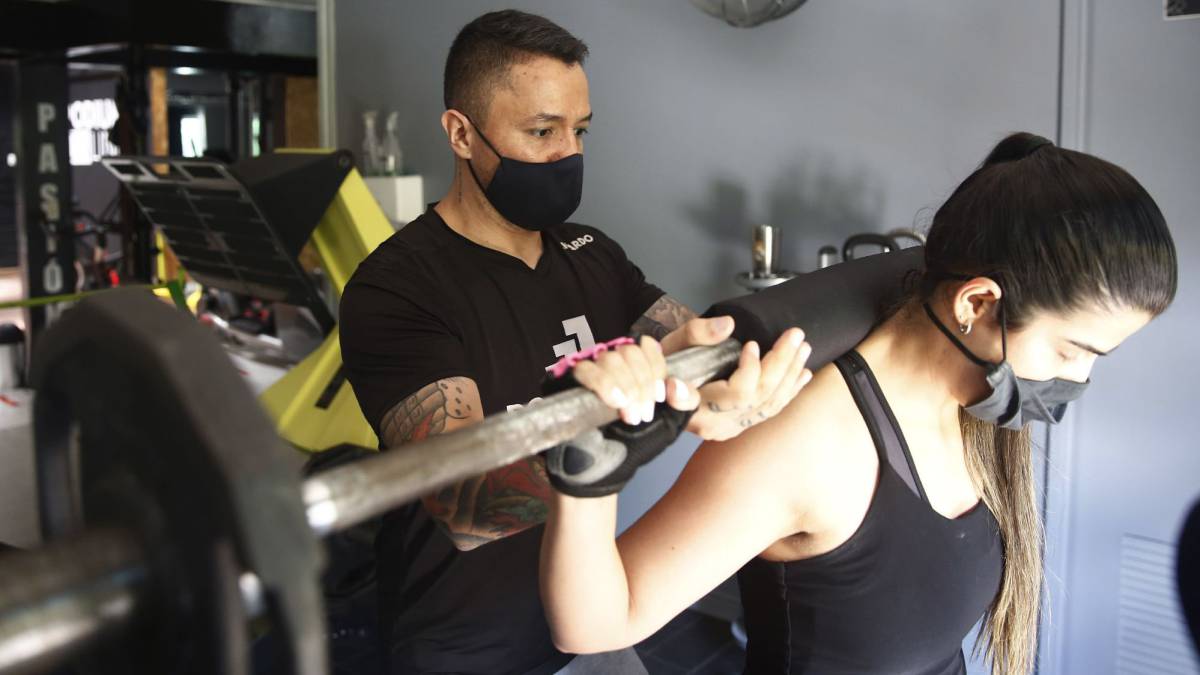 Entrenador sostenido la barra en los hombres de una chica.