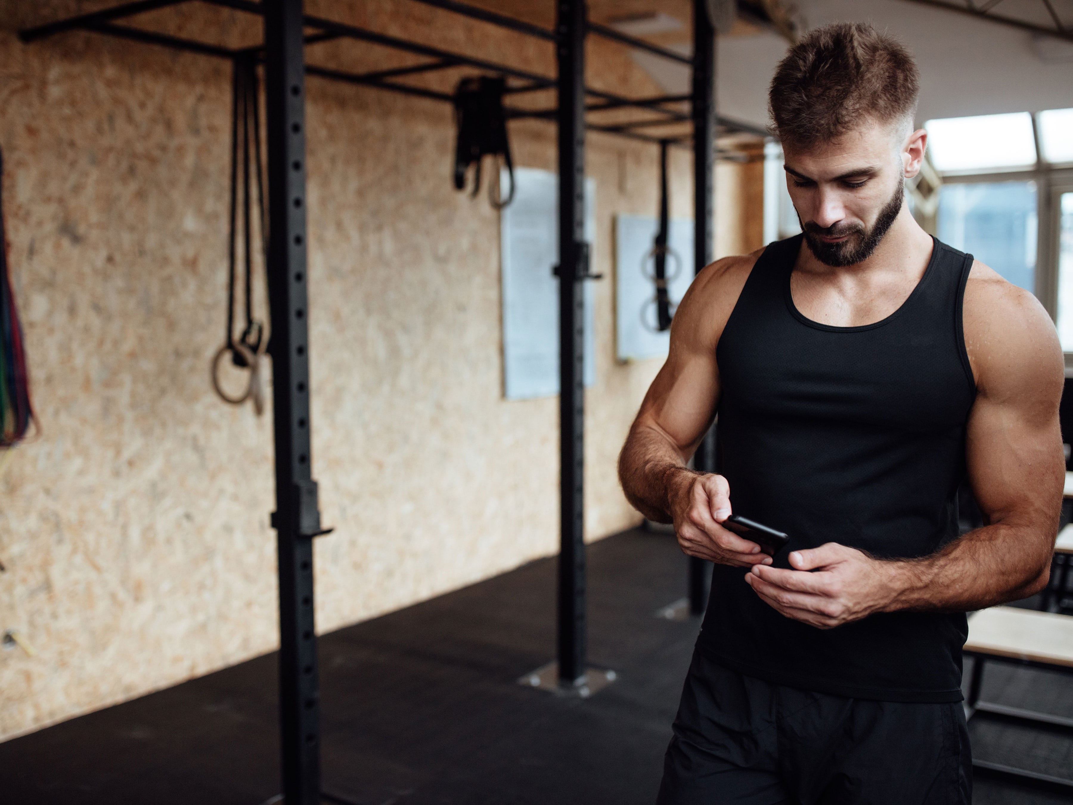 Chico musculoso con un celular en sus manos.