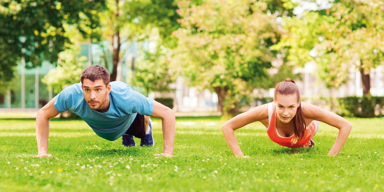 Chica junto con su entrenador, haciendo lagartijas en un espacio abierto.