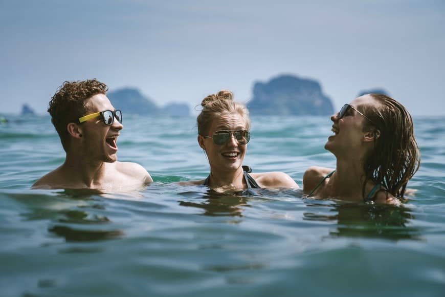 Tres jóvenes nadando en un lago