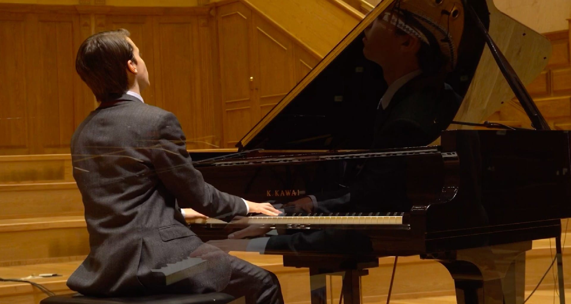 Pianista joven interpretando el piano, de espalda a los espectadores.