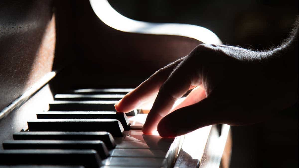 Mano tocando 3 teclas de un piano.