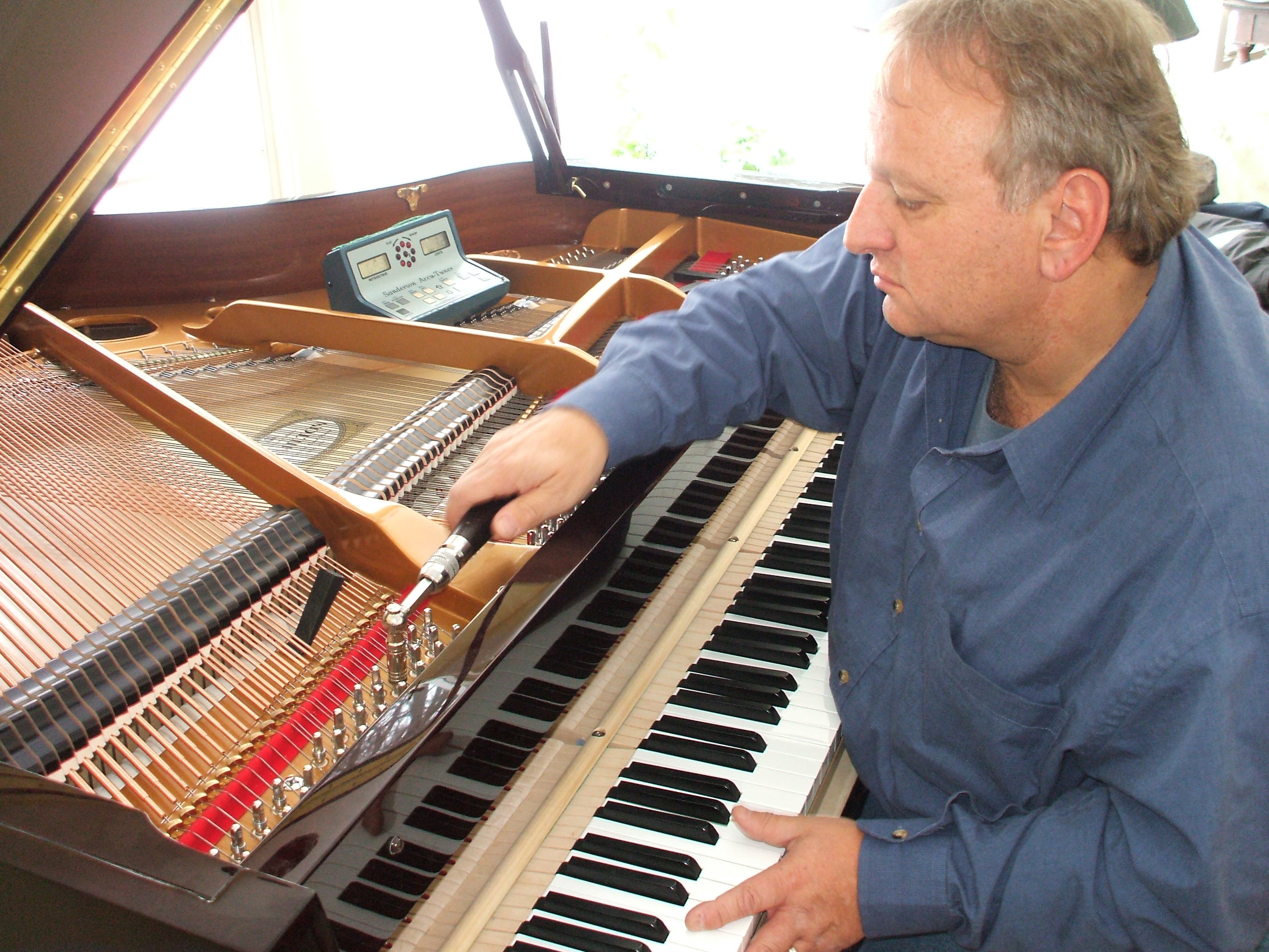 Hombre sentado frente aun piano, mientras lo ve fijamente.