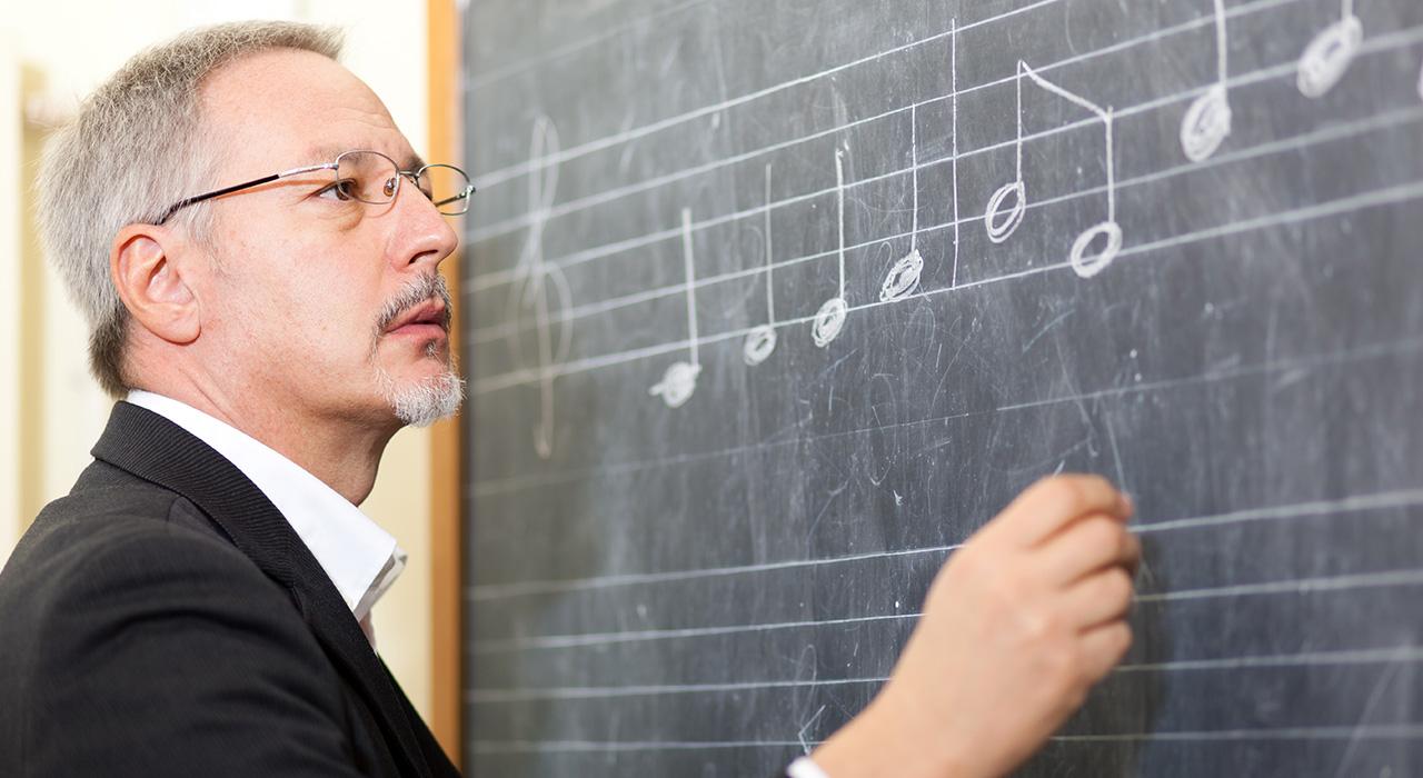 Profesor explicando notas musicales en un tablero.