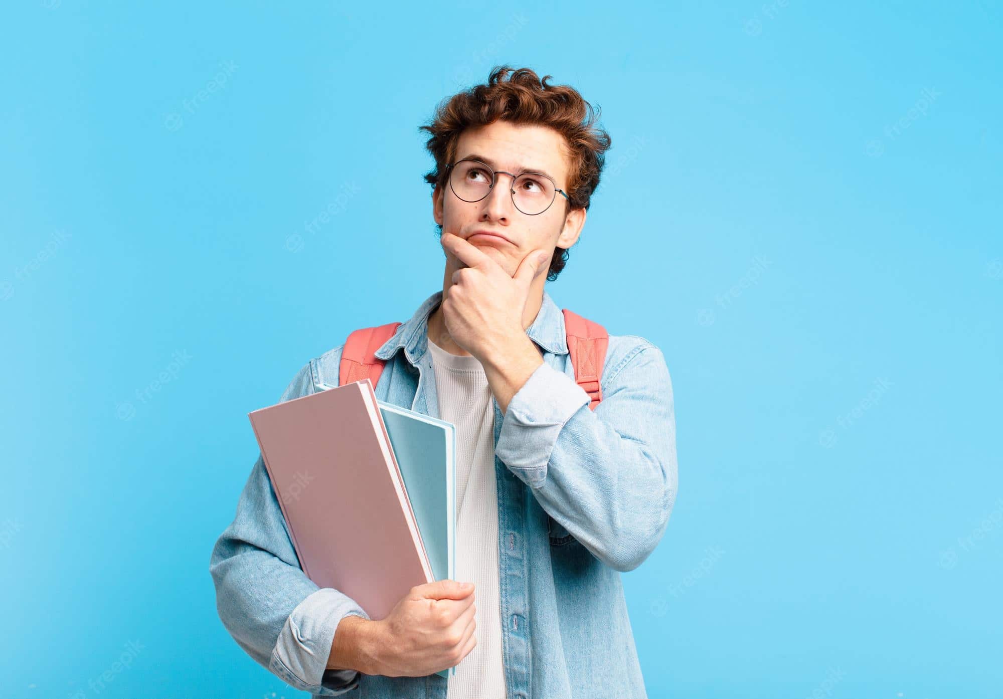 Joven pensando, mientras sostiene libros.