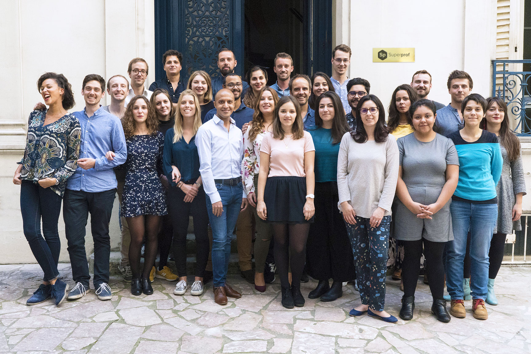 Grupo de personas que hacen parte del equipo de superprof, parados sonriendo junto a una puerta.