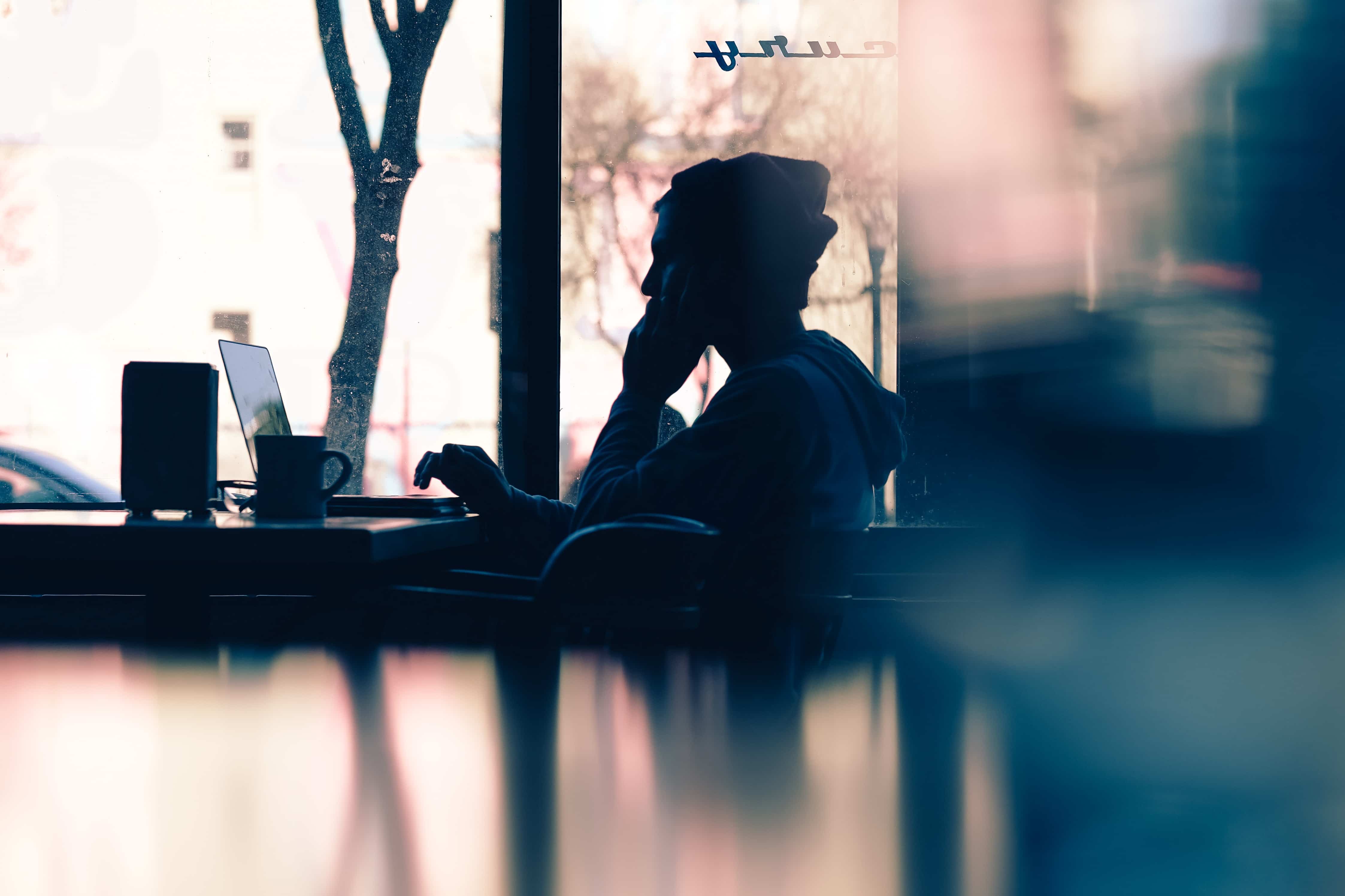 Silueta de mujer trabajando en su laptop con una taza de café