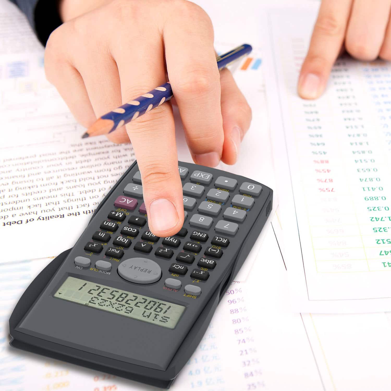 Mano sosteniendo un lápiz mientras maneja un calculadora.