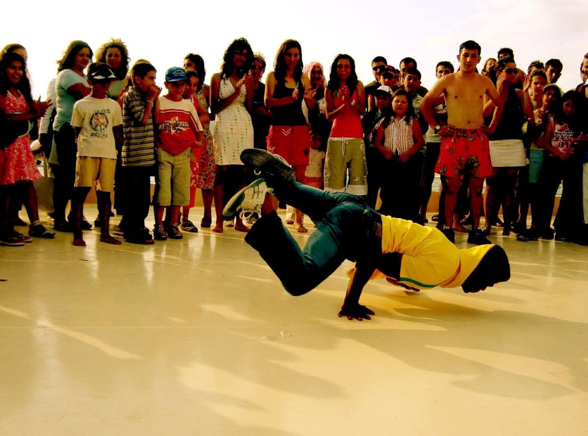 Grupo de gente mirando un joven bailar hip hop